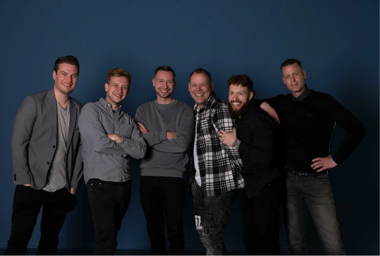 Het team van Rankingpartner staat lachend op de foto met blauwe achtergrond